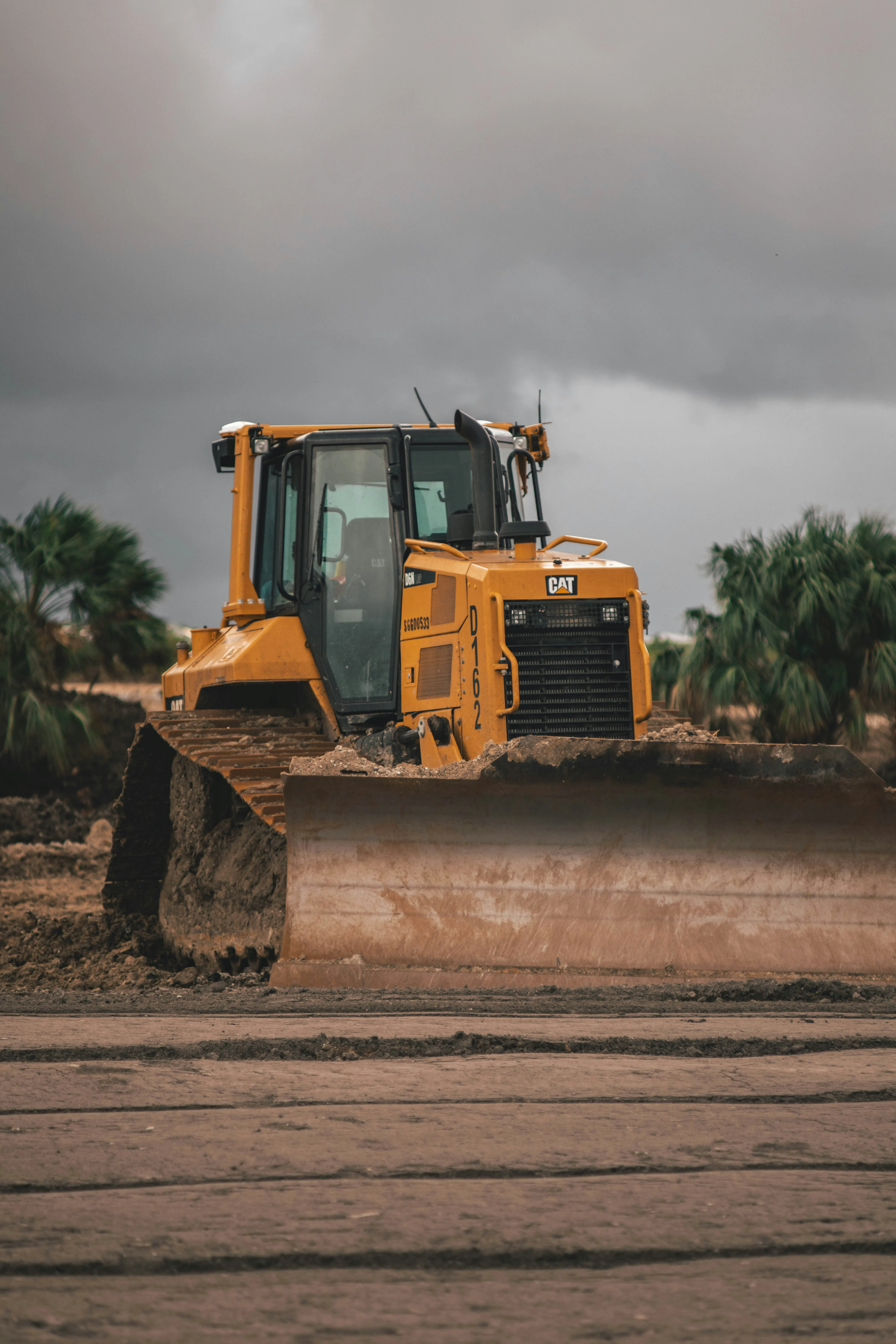 Heavy-duty yellow bulldozer with large blade on construction terrain with dirt and rocks